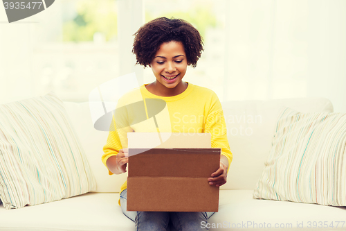 Image of happy african young woman with parcel box at home