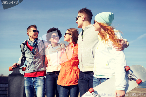 Image of happy teenage friends with longboards on street