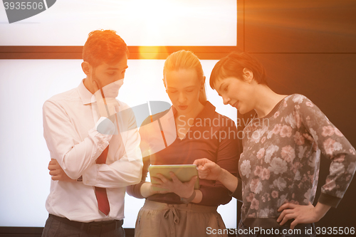 Image of young business people group working on tablet computer with sunr
