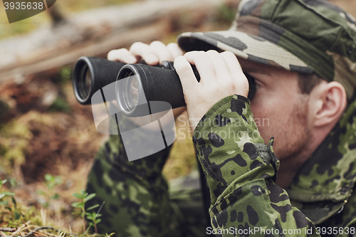 Image of young soldier or hunter with binocular in forest