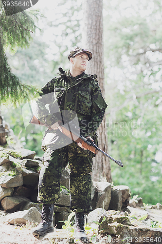 Image of young soldier or hunter with gun in forest