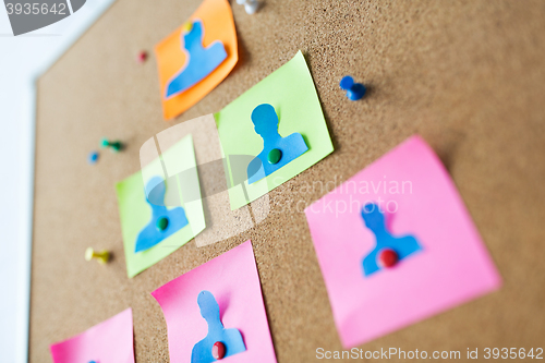 Image of close up of paper human shapes on cork board