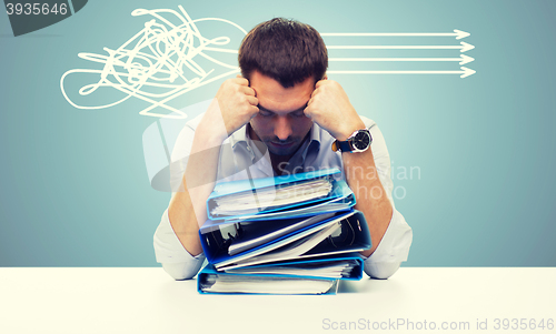 Image of sad businessman with stack of folders at office