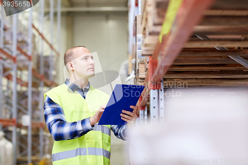 Image of man with clipboard in safety vest at warehouse