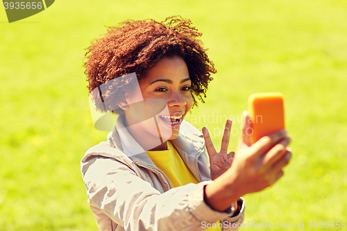 Image of happy african woman taking selfie with smartphone