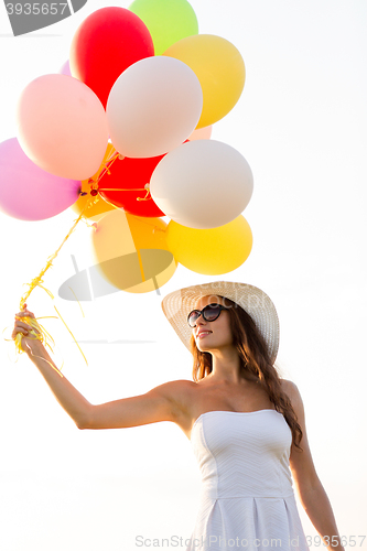 Image of smiling young woman in sunglasses with balloons