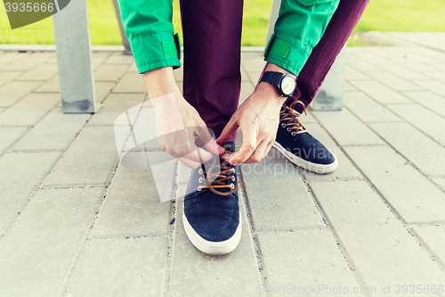 Image of close up of male hands tying shoe laces on street