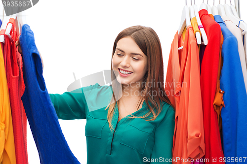 Image of happy woman choosing clothes at home wardrobe