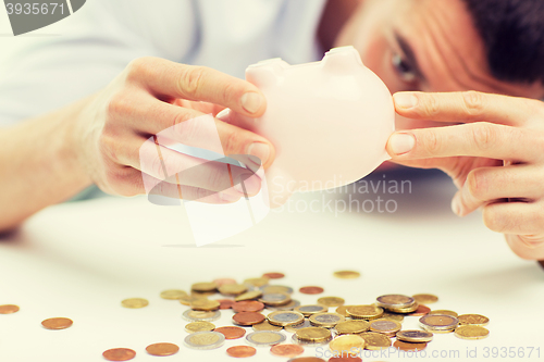 Image of close up of man pouring coins from piggy bank