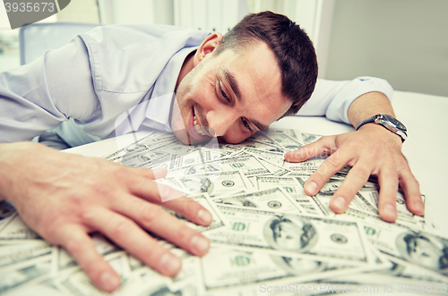 Image of happy businessman with heap of money in office