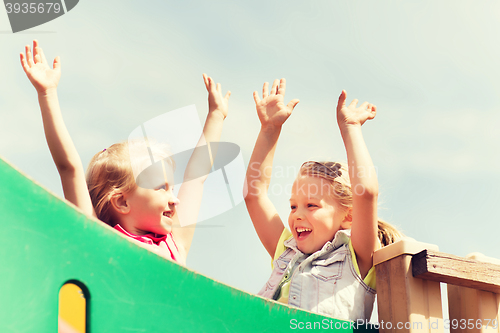 Image of happy girls waving hands on children playground