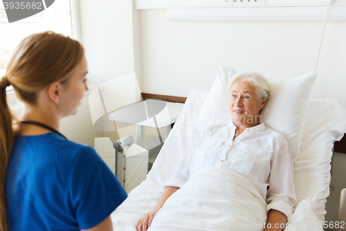 Image of doctor or nurse visiting senior woman at hospital
