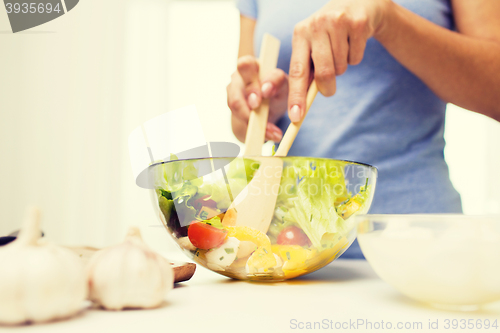 Image of close up of woman cooking vegetable salad at home