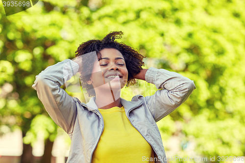 Image of happy african american young woman in summer park