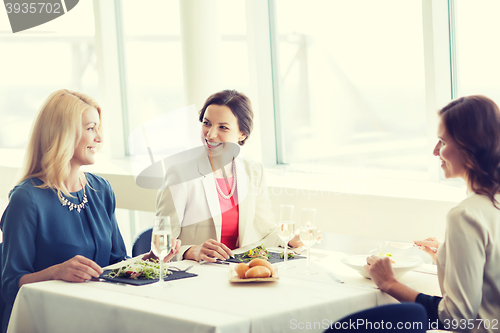 Image of happy women eating and talking at restaurant