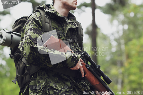 Image of close up of soldier or hunter with gun in forest