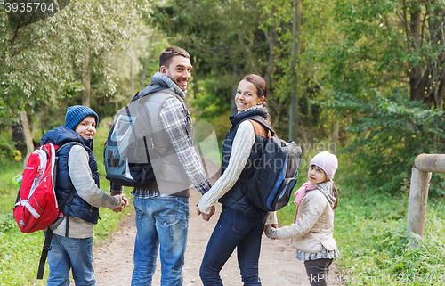 Image of happy family with backpacks hiking in woods