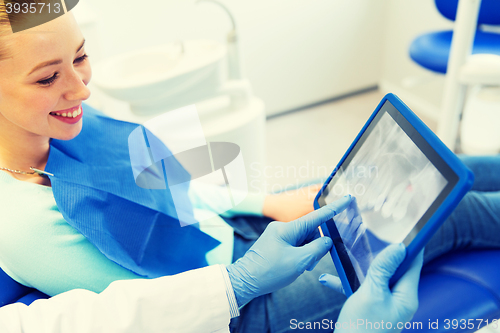 Image of dentist with teeth x-ray on tablet pc and woman