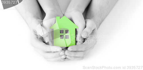 Image of man and woman hands with green paper house