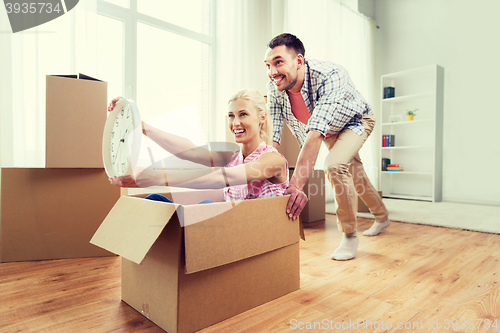 Image of couple with cardboard boxes having fun at new home