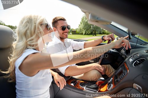 Image of happy couple using gps navigator in cabriolet car