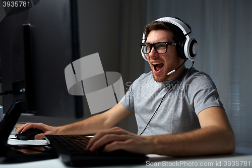 Image of man in headset playing computer video game at home