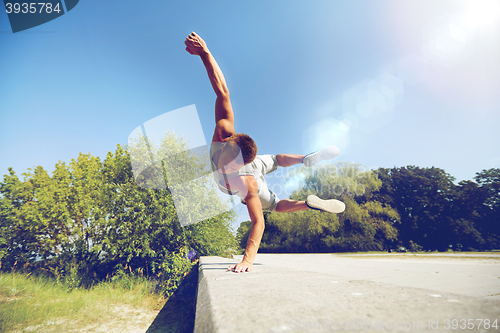 Image of sporty young man jumping in summer park