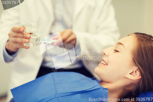 Image of happy dentist showing jaw layout to patient girl