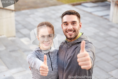 Image of smiling couple showing thumbs up on city street