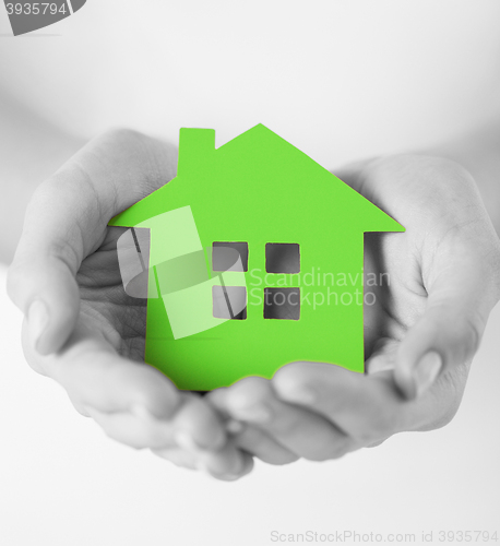 Image of hands holding green paper house