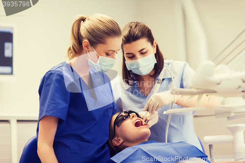 Image of female dentists treating patient girl teeth