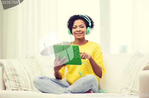 Image of happy african woman with tablet pc and headphones