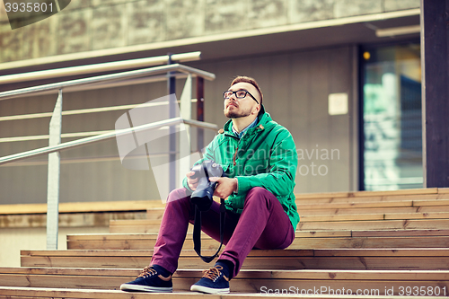 Image of young hipster man with digital camera in city