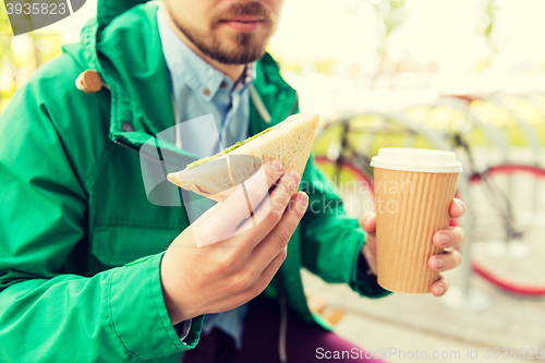 Image of close up of man with coffee and sandwich on street