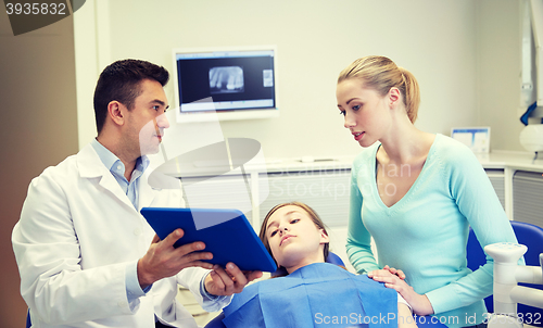 Image of dentist showing tablet pc to girl and her mother