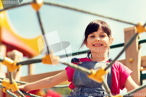 Image of happy little girl climbing on children playground