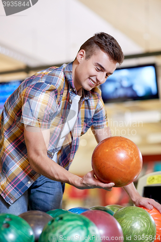 Image of happy young man holding ball in bowling club