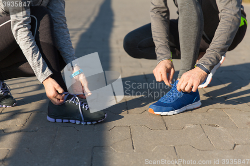 Image of close up of couple tying shoelaces outdoors