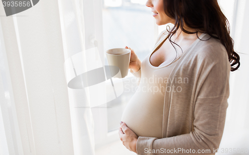 Image of close up of pregnant woman with tea cup at window