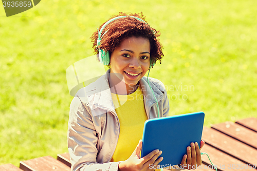 Image of happy african woman with tablet pc and headphones