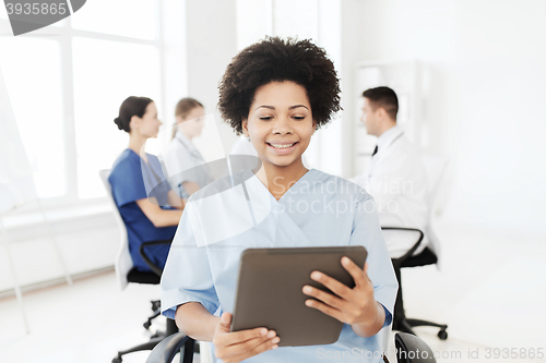 Image of happy nurse with tablet pc over team at hospital