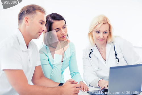 Image of doctor with patients looking at laptop