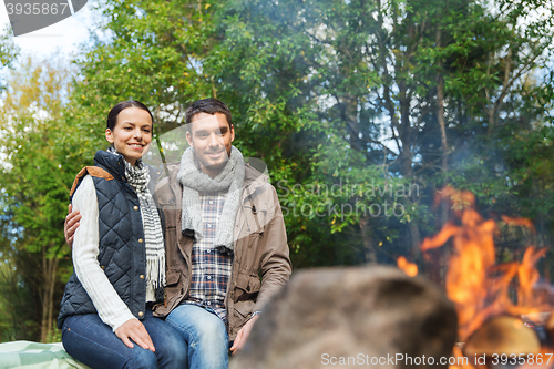 Image of happy couple sitting on bench near camp fire