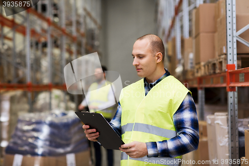 Image of man with clipboard in safety vest at warehouse