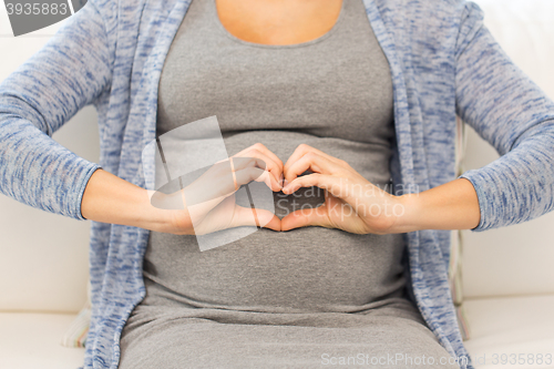 Image of close up of happy pregnant woman making heart