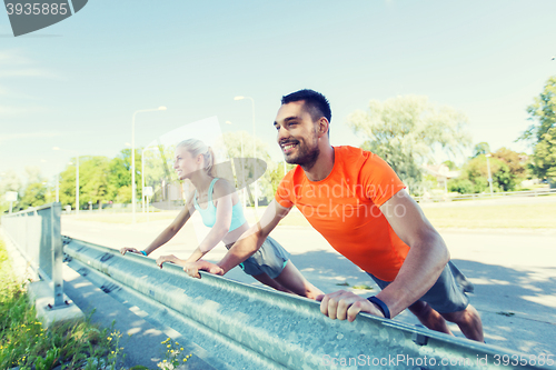 Image of close up of happy couple doing push-ups outdoors