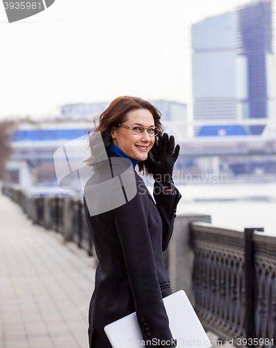 Image of friendly brunette with a computer outdoors