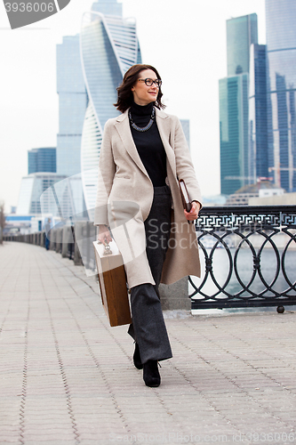 Image of woman with a wooden case in his hand in the bright coat