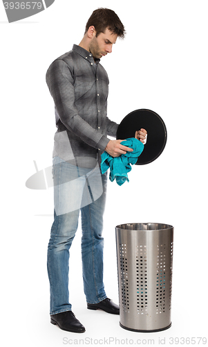 Image of Young man putting a dirty towel in a laundry basket