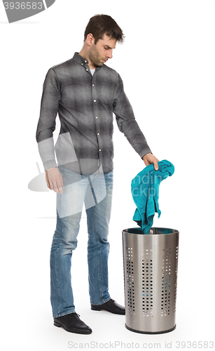 Image of Young man putting a dirty towel in a laundry basket